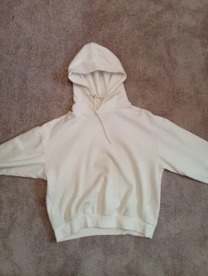 Vit hoodie från 157 med huva - Säljer en enkel och clean vit hoodie från 157 i storlek XS. Tröjan har en klassisk huva med snörning och ribbade muddar vid ärmslut och nederkant. Perfekt för chill dagar.