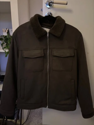 Teddyjacka i mocka  - Säljer en brun/grön teddyjacka med mjuk krage i teddy och två stora fickor framtill. Aldrig använd!!Materialet är mockaliknande med teddyfoder på kragen och på insidan, perfekt för kyliga dagar. ❣️Gav till min kille men den passade inte!!❣️