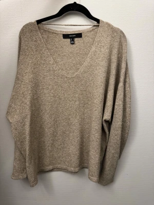 Beige stickad V-ringad tröja Vero Moda - Säljer en beige stickad tröja från Vero Moda med snygg V-ringning och lång ärm. Tröjan har en loose passform och är perfekt för dig som gillar en chill och enkel stil. Materialet är mjukt och skönt, passar bra till jeans eller kjol.
