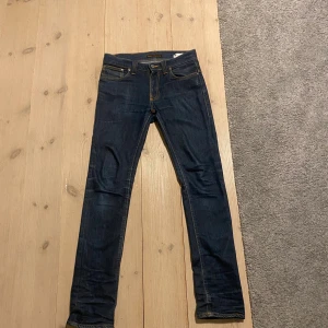 Nudie jeans raw denim  - Säljer nu dessa riktigt snygga nudie jeansen! Den här modellen kommer få en riktigt snygg fade när de används mer. Den ända nackdelen är ett lagat hål som syns på sista bilden men det syns ingenting när man har de på sig och det är bra lagat! 