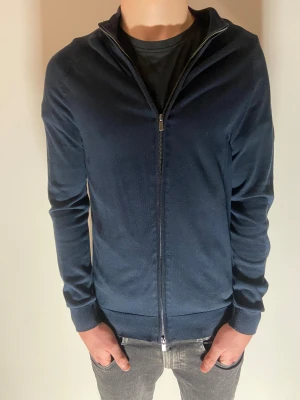Bruun & Stengade full zip - Tja! Säljer nu denna stilrena full zipen från Bruun & Stengade i storlek S | Tröja är marinblå vilket gör den lätt att styla med många olika färger | Gjord av 50% bomull och 50% lycocell. 8/10 skick