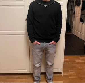 Svart långärmad tröja med half zip - Svart långärmad tröja med hög krage och snygg half zip-dragkedja framtill. Tröjan har ribbade muddar vid ärmslut och nederkant, vilket ger en clean och stilren look. Perfekt för dig som gillar enkel och tidlös stil. Jag på bilden är 165 