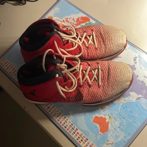 Nike Jordan 31 röda sneakers - Säljer ett par Nike Jordan 31 sneakers i rött och vitt med svart Jumpman-logga på sidan. Säljer dem väldigt billigt eftersom jag inte använder dem och bara vill bli av med dem. Skorna har högt skaft, snörning och en stickad ovandel som ger en cool textur. Sulan är röd med genomskinliga detaljer och logga undertill.  Funkar både inne och ute. Perfekt för dig som gillar basketstil.