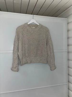Grå stickad tröja - Säljer en beige stickad tröja i 100% bomull från H&M i storlek S. Perfekt för dig som vill ha en mysig tröja att bara dra på sig en kylig dag!