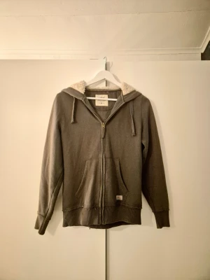 Zip-up  - Zip-up i en brun med en liten underton av grön färg. Den är väldigt skön på och insidan av luvan är lurvig 