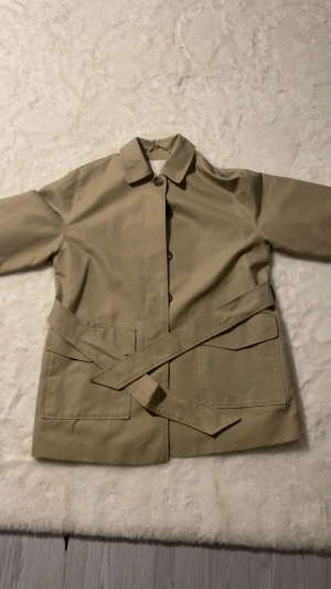 Trenchcoat HM - Helt ny bara ligger i garderoben och tar plats. Bälte vid midjan man knyter med. Kan gärna mötas upp ☺️