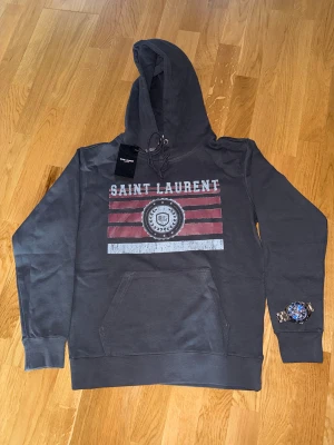 YSL hoodie - Säljer nu denna helt nya och trendiga YSL hoodien i strl M. Tags sitter kvar. Rekommenderar att du är ca 175-185 då jag är 184 o den sitter väldigt bra på mig. Bara att skriva ett DM vid intresse! (Likadan fast t shirt finns i min profil)