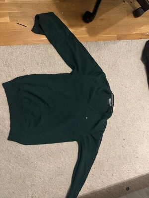 J.Lindeberg Merino sweatshirt  - Snygg mörkgrön stickad tröja från GANT med v-ringad hals och diskret logga på bröstet. Tröjan har långärmad passform och är gjord i mjukt material som känns skönt mot huden. Perfekt för dig som gillar stilrena och klassiska plagg.