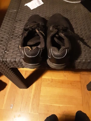 Svarta sneakers med mesh och snörning - Svarta sneakers med ovandel i mesh och syntet, klassisk snörning och rund tå. Skorna har diskreta reflexdetaljer baktill och platt sula, perfekt för en sportig och avslappnad stil.