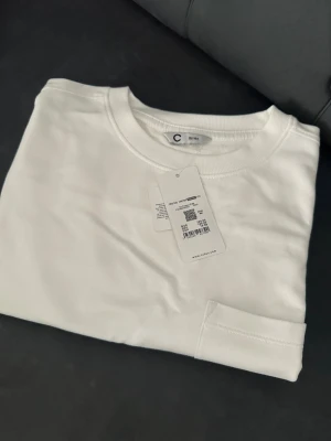 Vit långärmad tröja från Cubus - Vit långärmad tröja från Cubus i mjuk bomull. Tröjan har en rund halsringning och en enkel bröstficka som ger en clean och chill vibe. Perfekt för dig som gillar basic och stilrena plagg. Passar dig som vill ha en enkel look.