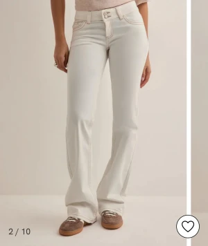 Vita bootcut jeans från Nelly - Snygga vita jeans från Nelly med bootcut passform och hög midja. Jeansen har klassiska fem fickor, kontrastsömmar och coola broderade detaljer på bakfickorna. Perfekt för dig som vill ha en fräsch och trendig look. Hata storlek 31/34 på LTB jeans och sitter precis som dessa men kan ej se vilken storlek dessa jeans är. Uppskatta - M/L