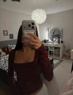 Vinröd långärmad topp med fyrkantig ringning - Säljer en vinröd långärmad topp från Bik Bok med snygg fyrkantig ringning. Toppen är figurnära och har en stilren, enkel design som passar perfekt till jeans eller kjol. Materialet är mjukt och stretchigt för en bekväm passform.