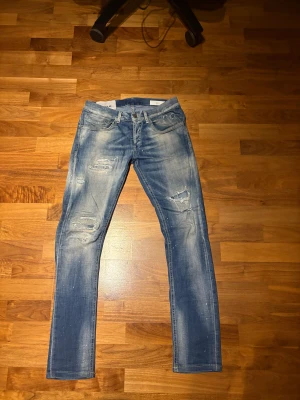 Dondup George - Säljer nu dessa riktigt feta Dondup George jeansen i en tvättad blå färg. De är storlek 30 och är i dunder skick förutom att Dondup loggan har lossnat lite som ni ser på bilderna, men inget som påverkar vid användning! Hör av er vid funderingar och kolla gärna in min profil för bundlepriser!