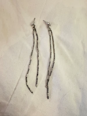 Långa silverfärgade kedjeörhängen - Säljer ett par långa, tunna örhängen i silverfärg med två kedjor per öra. Kedjorna har små runda och avlånga detaljer som ger ett stilrent och trendigt intryck. Perfekta för dig som gillar minimalistiska smycken med lite extra edge.