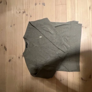 Grå tröja från Polo Ralph Lauren - Snygg grå tröja från Polo Ralph Lauren med klassisk broderad logga på bröstet. Tröjan har rund hals och långa ärmar, perfekt för dig som gillar stilrena och tidlösa plagg. Materialet är mjukt och skönt, passar till många olika outfits.