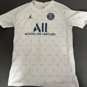  PSG fotbollströja - Säljer en vit PSG fotbollströja från Jordan i mycket bra skick. Tröjan har korta ärmar och ett diskret mönster med texten 'PARIS' över hela tyget. Den har också PSG:s emblem och Jordan-loggan på bröstet. Perfekt för fotbollsfans som vill ha en stilren look! Är i ganska bra skick köpt från Frankrike för 890 pris kan diskuteras 