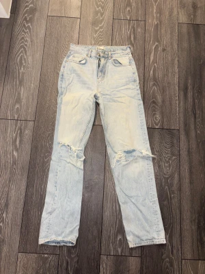 Ljusblå jeans med slitna knän - Säljer ett par ljusblå jeans från Gina tricote med hål på knän. Super fina.