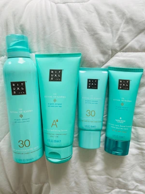 Rituals The Ritual of Karma hudvård - Fyra produkter från Rituals The Ritual of Karma-serien: solskyddsspray SPF 30, återfuktande after sun lotion med aloe vera, solskyddskräm för ansiktet SPF 30 och handkräm med hydra-boost complex. Alla i snygga turkosa förpackningar, perfekt för dig som gillar fräsch hudvård.