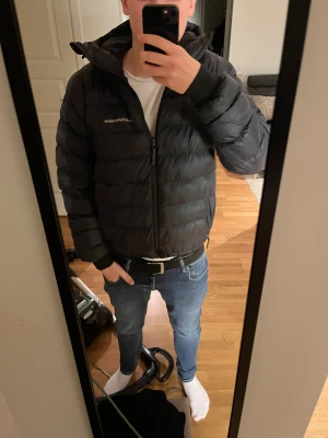 Svart dunjacka Peak Performance M - Säljer en svart dunjacka från Peak Performance i storlek M. Jackan har huva, dragkedja framtill och diskret logga på bröstet och ärmen. Puffig modell som håller värmen och passar perfekt till kyliga dagar. Snygg och stilren design. Knappt använd max 20 ggr.