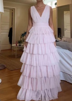 Rosa Balklänning  - Säljer nu min fina balklänning 😍 Den är ljusrosa, lång och har en fluffig tyllkjol med volanger. Superbekväm och rör sig så fint när man går. Perfekt till balen!  Hör av dig om du vill ha fler bilder ❤️Använd endast en gång.  