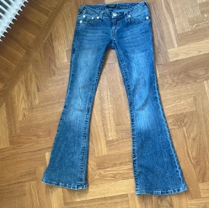 True Religion blå bootcut jeans - Säljer dessa supersnygga blåa jeans från true religion i nytt skick. Sömmarna på jeansen är i en ljusrosa färg. Dem är köpta i butiken Nelly på Drottninggatan i Stockholm. Byxan är designad så att färgen ser lite urtvättad ut, så coolt!
