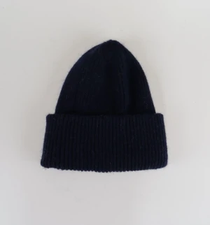 Satinfodrad mössa marinblå - Denna riktigt snygga stickade mössa ger en lyxig och exklusiv känsla samtidigt som den håller en stilren och tidlös design. På insidan finns det ett insytt lager av satin som både skyddar håret och ger extra komfort. Denna kombination av stil och funktionalitet gör den till ett självklart val för dig som söker en mössa av elegans. Mössan är unisex och onesize.😁