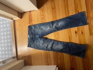 Blå bootcut jeans med pärldetaljer - Snygga blå jeans från Internacionale i bootcut-modell med coola pärldetaljer på bakfickorna. Köpte på Plick men säljer vidare då de tyvärr är lite för korta för mig!💕 pris kan diskuteras, skriv om ni skulle ha frågor!💕