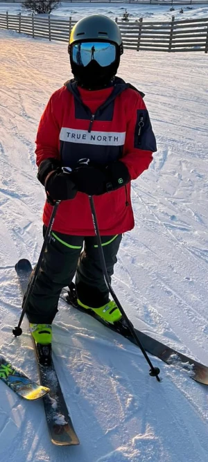 Röd skidjacka True North med huva - Säljer en röd och mörkblå vindjacka från True North med stor huva och half zip framtill. Jackan har en stor ficka med dragkedja på magen, samt en extra ficka med dragkedja på ärmen. Snyggt tryck med logga över bröstet och svarta muddar vid ärmslut. Den har en liten repa på den inbyggda "buffen"