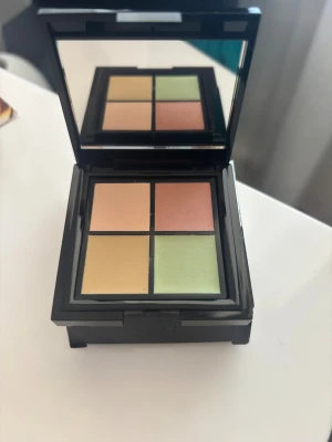 By Lyko concealerpalett med fyra nyanser - Concealerpalett från By Lyko med fyra krämiga nyanser: beige, persika, gul och grön. Perfekt för att täcka mörka ringar, rodnad och ojämnheter. Kommer i en stilren svart ask med spegel i locket, smidig att ha med i väskan.