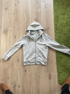 Grå hoodie från Polo Ralph Lauren - Säljer nu denna feta tröja då den inte kommer till användning längre, den är storlek S och är i bra skick. Det ända är att det är väldigt små gula prickar på den ena nedre armen men som inte syns knappt, syns på sista bilden. Hör gärna av er vid funderingar😊