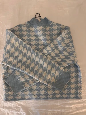 Blåvit rutig stickad tröja Divided - Säljer en snygg stickad tröja från Divided i storlek S. Tröjan har ett blåvitt rutigt mönster, ribbad hals och muddar vid ärmslut. Perfekt för dig som gillar coola mönster och vill ha en mysig och trendig look.