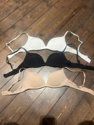 3-pack Intimissimi gioia 75C - Säljer tre släta linnetoppar från Intimissimi i färgerna vit, svart och beige. Alla har justerbara axelband och mjuka kupor för en clean look under kläder. Perfekt för dig som vill ha basic och bekvämt. Materialet är mjuk syntet med stretch.