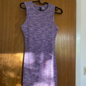 Lila ribbad kortklänning H&M XS - Säljer en lila och rosa ribbad kortklänning från H&M i storlek XS. Klänningen är ärmlös med rund hals och har ett snyggt melerat mönster. Materialet är mjukt och stretchigt, perfekt för dig som gillar bekväma och trendiga plagg.