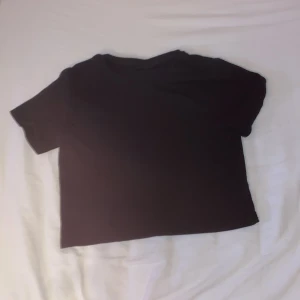 Svart croppad t-shirt från LMTD - En basic svart t-shirt från LMTD i croppad modell. T-shirten har rund halsringning och korta ärmar. Tillverkad i mjuk bomull som är skön mot huden. Perfekt till jeans eller kjol för en enkel och clean look.