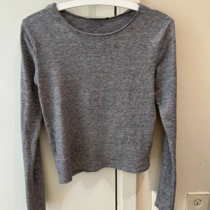 Grå långärmad stickad tröja - En enkel och stilren grå långärmad tröja i mjukt stickat material. Modellen har rund hals och en normal passform som sitter snyggt på kroppen. Perfekt att matcha med jeans eller kjol för en chill look. Jag kan säga det är som S i storlek 