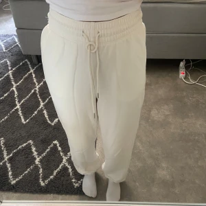 Vita mjukisbyxor från H&M XS - Vita mjukisbyxor från H&M i storlek XS. Byxorna har hög midja med bred resår och snörning i midjan. Tillverkade i en mjuk bomulls- och polyestermix med borstad insida för extra komfort. Perfekta för en chill och avslappnad stil.