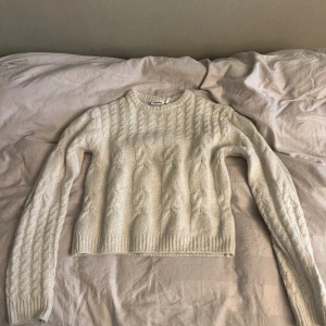 Vit stickad tröja från Weekday - Säljer en vit stickad tröja från Weekday i storlek M. Tröjan har ett snyggt flätmönster över hela och är långärmad med ribbade muddar vid hals, ärmslut och nederkant. Perfekt för dig som gillar en klassisk och cozy look.