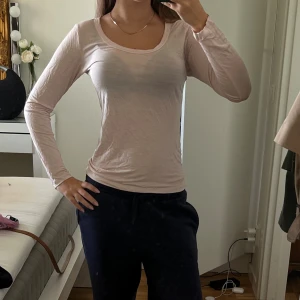 Ljusrosa långärmad topp i bomull - Säljer en ljusrosa långärmad topp med rund halsringning. Modellen är tight och sitter snyggt mot kroppen. Tillverkad i tunn och mjuk bomull, perfekt för lager-på-lager eller som den är. Enkel och stilren design som passar till det mesta.