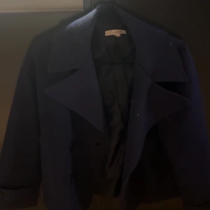 Mörkblå skepparkavaj från DesignSi XS/S - Stilren mörkblå skepparkavaj från DesignSi i klassisk modell med bred krage och dubbelknäppning. Jackan är fodrad och har en rak passform som ger en snygg siluett. Perfekt för dig som gillar tidlös och cool stil.