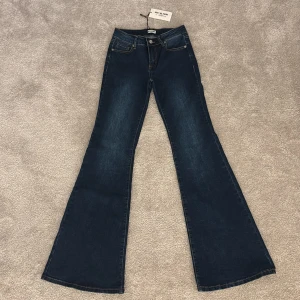 Blå bootcut jeans med spetsdetalj  - Mörkblå bootcut jeans från Meet Me There (Fillipa kollektion) med snygga spetsdetaljer på bakfickorna. Storlek xxs/xs. Jeansen är ganska långa ungefär 110 cm. Helt nya, inte ens provade. KÖP NUU!! 💕💕💕ordinarie pris 900 kr 
