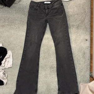 Svarta bootcut jeans från Junkyard - Säljer ett par svarta bootcut jeans från Junkyard i storlek S. Jeansen har klassisk femficksdesign, snygga bakfickor med unik söm och dragkedja fram. Materialet är jeans och färgen är en tvättad svart nyans. Använda en gång, säljer för dem är lite för stora för mig.