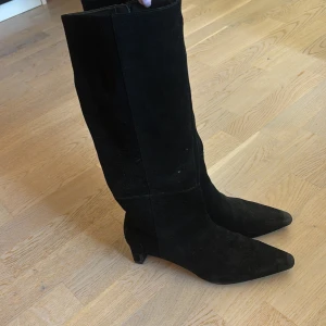 Svarta mockastövlar med klack - Snygga svarta stövlar i mocka med spetsig tå och låg klack, säljes då de inte kommer till användning längre! Är osäker på vart de kommer ifrån då lappen försvunnit!