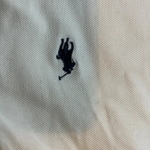 Vit pikétröja Polo Ralph Lauren M - Vit pikétröja från Polo Ralph Lauren med klassisk krage, två knappar och den ikoniska broderade polospelaren på bröstet. Tröjan är i bomull och har korta ärmar. Perfekt för en clean och stilren look.