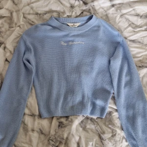 Ljusblå stickad tröja från H&M - Superfin ljusblå stickad tröja från H&M med broderad text 'New Hampshire' framtill. Tröjan har ribbad struktur, rund halsringning och långa ärmar. Perfekt för lager-på-lager och chill dagar.