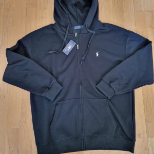 Svart hoodie från Polo Ralph Lauren - Säljer en helt ny Polo Ralph Lauren zip-hoodie. Står 3XL men passar XL !!!