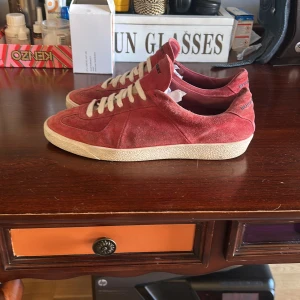 Röda mockasneakers från Burberry - Snygga röda sneakers från Burberry, storlek 43 bra skick inga defekter bara lite smutsiga. Man får med extra snören. Pris kan diskuteras, skriv om ni har fler frågor!