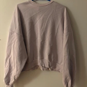 Ljusrosa sweatshirt med rund hals - Enkel och stilren ljusrosa sweatshirt med rund halsringning och ribbade muddar. Tröjan har en loose passform och är perfekt för en avslappnad look. Mjuk och skön, passar till många olika outfits.