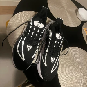 Adidas Boost svarta och vita sneakers - Säljer ett par Adidas Boost sneakers i svart och vitt med snygga kontrasterande detaljer och sportig design. Skorna har snörning, mesh- och syntetmaterial samt en tjock, bekväm sula för extra komfort. Perfekta för dig som gillar streetstyle och sportig vibe.