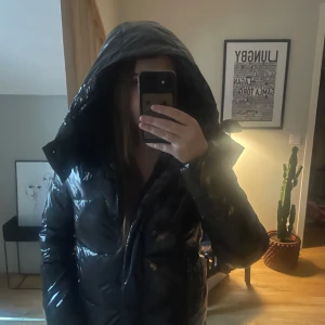 Svart pufferjacka från Calvin Klein Jeans - Säljer en svart, glansig pufferjacka från Calvin Klein Jeans med huva och dragkedja. Jätte bra skick! pris kan diskuteras 