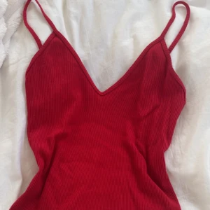 Röd ribbad topp från Brandy Melville - Säljer en super snygg röd ribbad topp från Brandy Melville med smala axelband och v-ringning. Klänningen är tillverkad i 100% bomull och har en tight passform. Är one-size men skulle säga att den passar xs-s. Säljer då den har aldrig kommit till användning💕💕